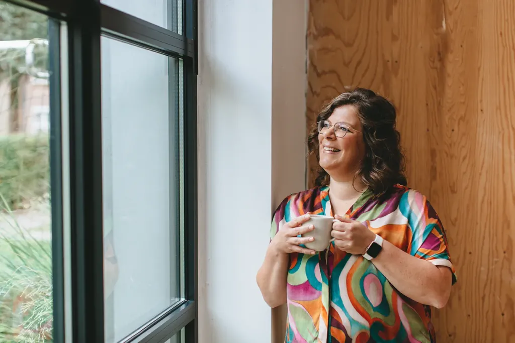 Janneke Fleuren met een kop koffie bij het raam